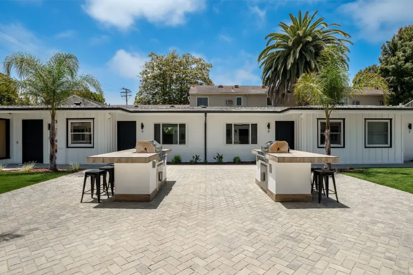 Outdoor patio area featuring stainless steel BBQ grills and bar stools.