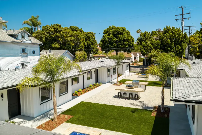 Low-angle shot of a white apartment complex under a clear blue sky.