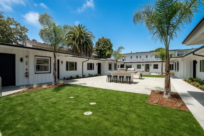 Wide shot of a clean, paved courtyard between white residential units.