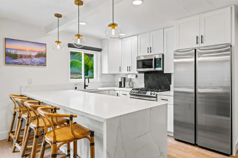 Modern white kitchen with a center island and stainless steel appliances.