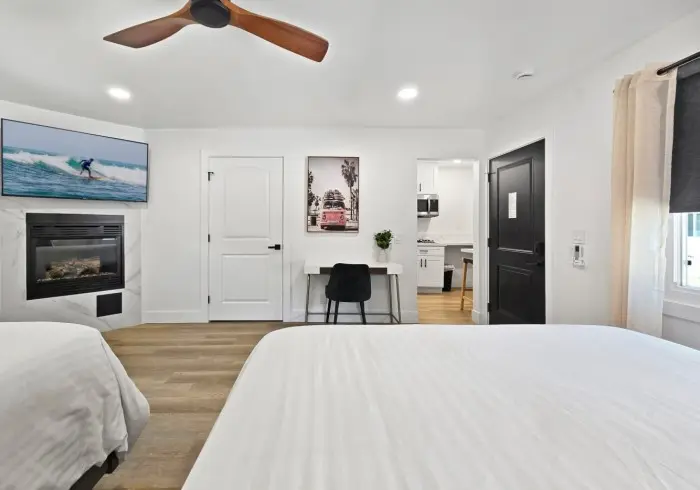 Bedroom with fireplace, desk, and TV in Deluxe Queen suite.