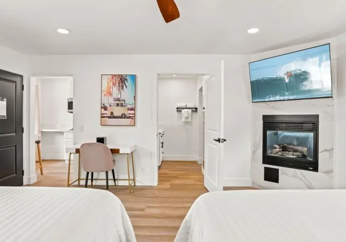 Bedroom with wall-mounted TV, desk, and fireplace in Deluxe Queen room.