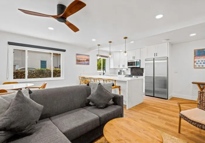 Penthouse living room with cozy sofa and view of kitchen.